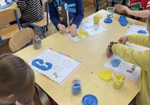 Dzieci uzupełniają ciastoliną szablony które prezentują symbole pogody.
