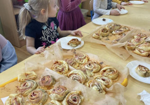 Dzieci próbują upieczonych przygotowanych przez siebie ślimaków z ciasta francuskiego.
