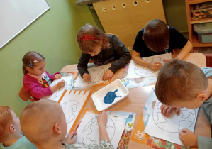Dzieci skupione na kolorowaniu pracy patyczkami kosmetycznymi.