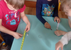 Dzieci grają w grę z kostką i taśmą metrowa