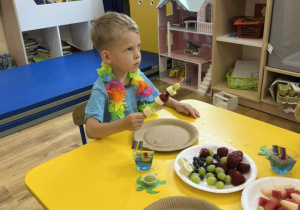 Zdjęcie przedstawiające chłopca podczas robienia szaszłyków owocowych.