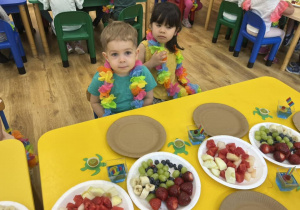 Zdjęcie przedstawiające dzieci siedzące przy stolikach przed rozpoczęciem robienia szaszłyków