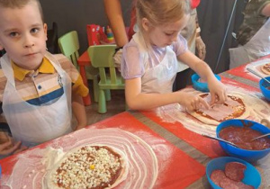 Filip wykonał już swoją pizzę a Ola jeszcze układa szynkę.