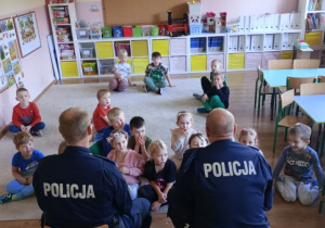 Dzieci z uwagą słuchają wypowiedzi policjantów.