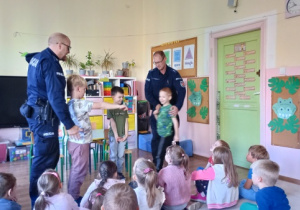 Policjanci uczą dzieci, jak bezpiecznie przejść przez jezdnię.