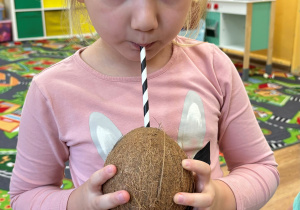 Matylda pije przez słomkę wodę z kokosa