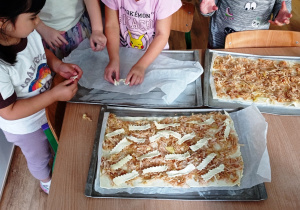 Dziewczynki układają paski z ciasta na startych jabłkach