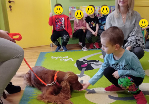 Mikołaj daje rękę pieskowi do polizania.