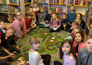 Dzieci siedzą na dywanie w bibliotece