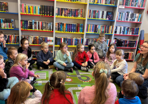 Dzieci siedzą na dywanie w bibliotece