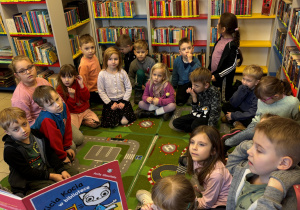 Dzieci siedzą na dywanie w bibliotece