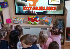 Dzieci oglądają film edukacyjny o kotach