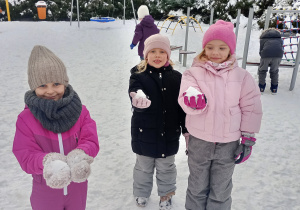 Dziewczynki pokazują ulepione przez siebie kule śniegu.