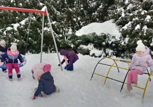 Dzieci bawią się śniegiem na placu zabaw.