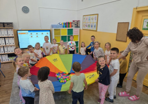 Dzieci radośnie oczekują na zabawę z chustą animacyjną i kolorowymi kulkami