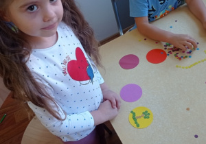 Dziewczynka pokazuje swój obrazek z papierowych kropek.