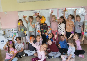 Grupa przedszkolaków pozujących wspólnie z kolorowymi kropkami podczas obchodów Dnia Kropki.
