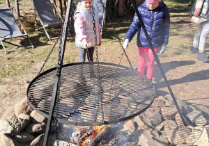 Dziewczynki pieką pianki przy ognisku.