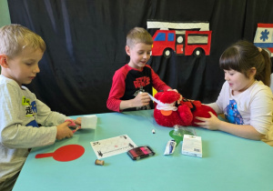 Dzieci bandażują pluszowego misia.