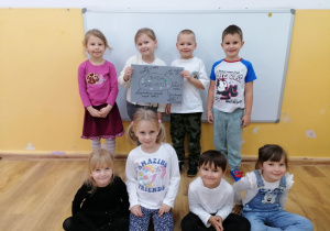 Grupa dzieci pozuje z plakatem „Rada Dzieci” na tle sali.