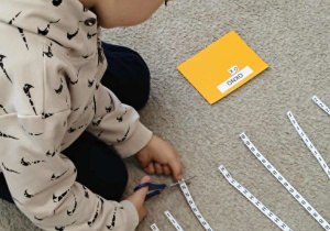 Chłopiec odcina nożyczkami literę.