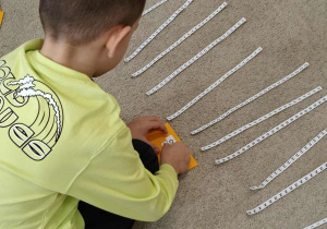 Chłopiec odcina nożyczkami literę.