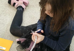 Dziewczynka odcina nożyczkami literę.