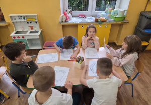 Grupa dzieci szuka litery "O" wśród wyrazów na kartce.