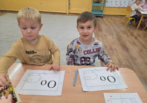 Dwójka dzieci pracuje z kartą pracy, która przedstawia dużą i małą literę „O”.