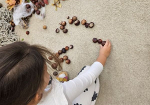 Dziewczynka układa kompozycję jesienną.