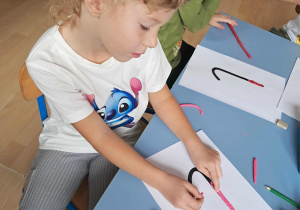 Dziewczynka wykleja plasteliną literkę l.