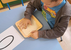 Chłopiec pisze na mannie literkę o.