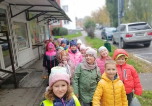 Dzieci stoją w parach przed sklepem.