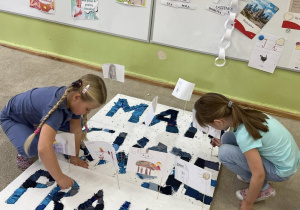 Dwie dziewczynki wypełniają kolorowymi materiałami duże napisy „MAM SWOJE PRAWA” na białych planszach.