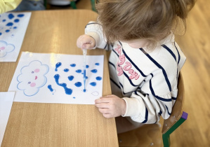 Amelka umieszcza krople wody pod chmurą.