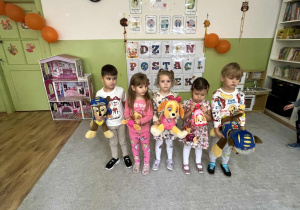 zieci stoją z maskotkami.