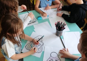 Dzieci kolorują obrazki ze smerfami.