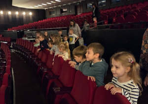 Grupa dzieci ogląda dużą salę teatralną i siedzenia widowni.