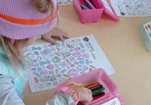 Dziewczynka koloruje i liczy obrazki.