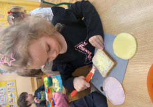 Dziewczynka smaruje masłem chleb.