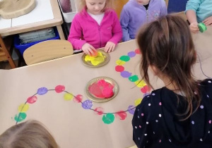 Dzieci ozdabiają obrus z wykorzystaniem stempelków.