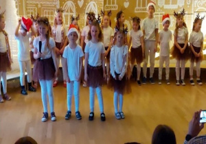 Czwórka dzieci stojąc z przodu śpiewa do mikrofonu.