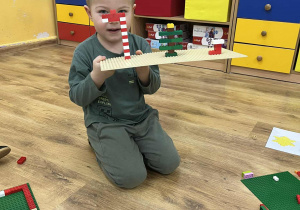 Chłopiec trzyma budowlę.