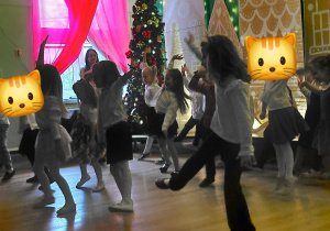 Dzieci prezentują układ taneczny w świątecznej scenerii.