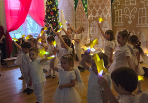 Dzieci trzymają świecące gwiazdki podczas występu bożonarodzeniowego.