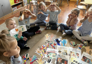 Zdjęcie przedstawiające dzieci siedzące na dywanie podczas robienia plakatu z prawami dziecka.