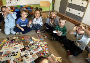 Zdjęcie przedstawiające dzieci siedzące na dywanie podczas robienia plakatu z prawami dziecka.