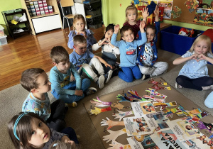 Zdjęcie przedstawiające dzieci siedzące na dywanie podczas robienia plakatu z prawami dziecka.