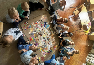 Zdjęcie przedstawiające dzieci siedzące na dywanie podczas robienia plakatu z prawami dziecka.