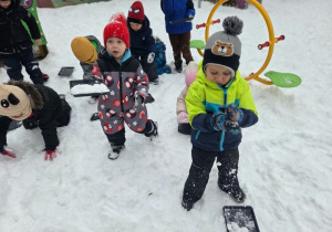 Dzieci bawią się śniegiem, ugniatają go i przenoszą na tackach.